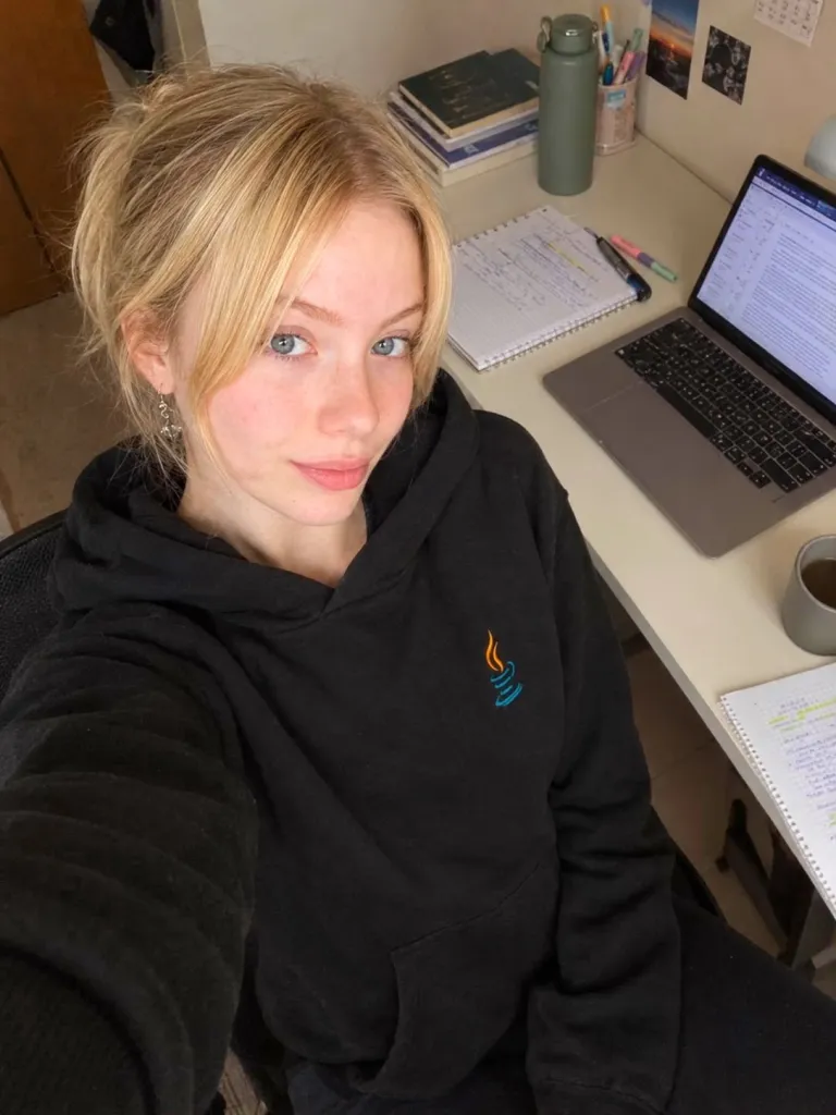 Alice Scherer na mesa de estudos, com o notebook aberto e um moletom do Java